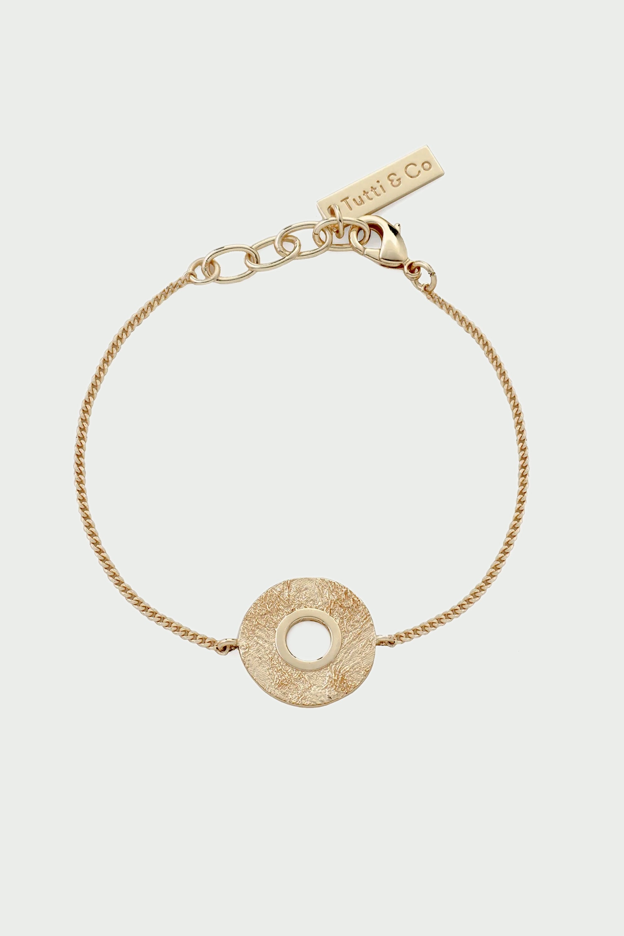 Gold bracelet with a circular design on a light gray background